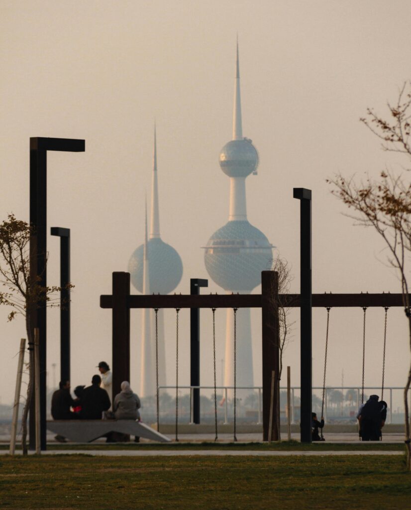 Captivating view of Kuwait Towers in a foggy morning with swings and people.